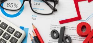 sheets with graphs, pencils, glasses, and percentage toys on the table