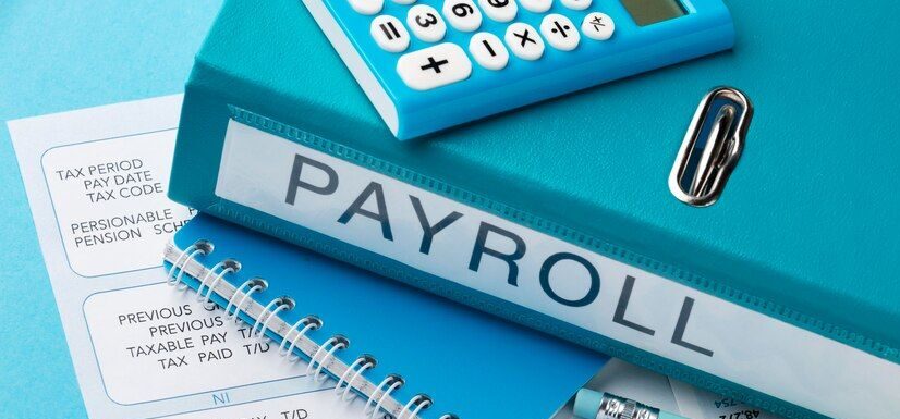 file labeled payroll and printed sheets under it are laying on a desk-Payroll-image